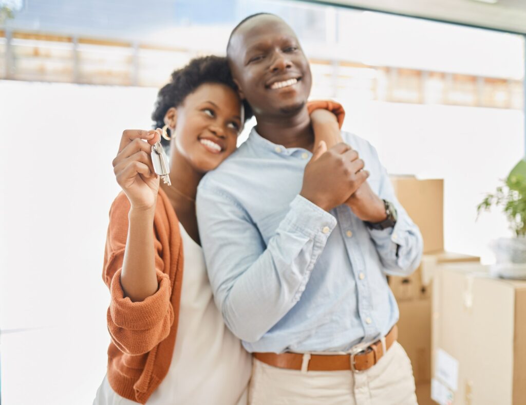 Happy homeowners. Shot of a young couple showing the keys to their new house.