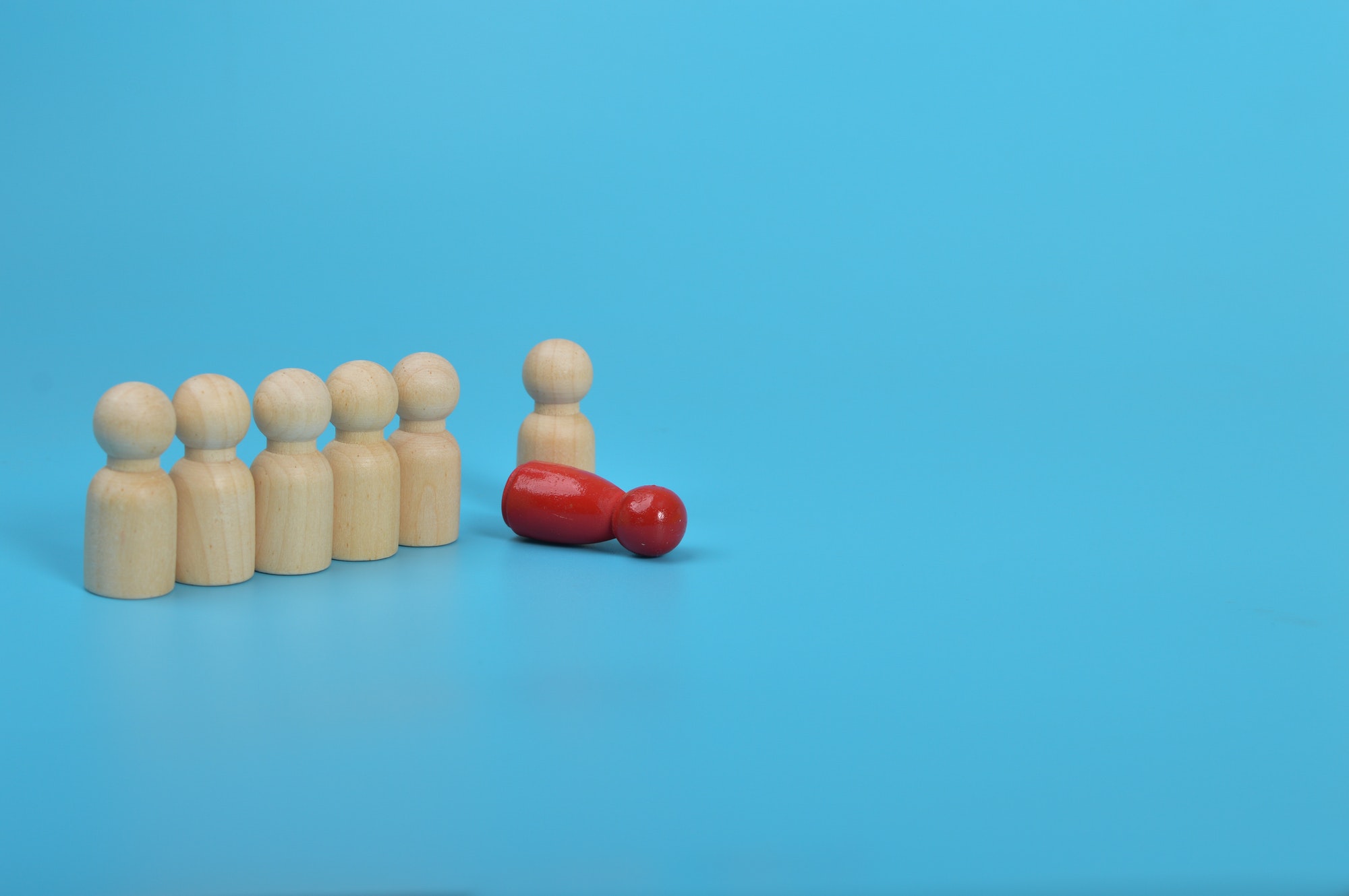 Dismissal, layoff, unemployment, employment stress.Red wooden figures overturns row group of workers